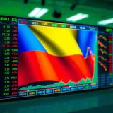 Stock market data displayed on digital screen with Colombian flag background